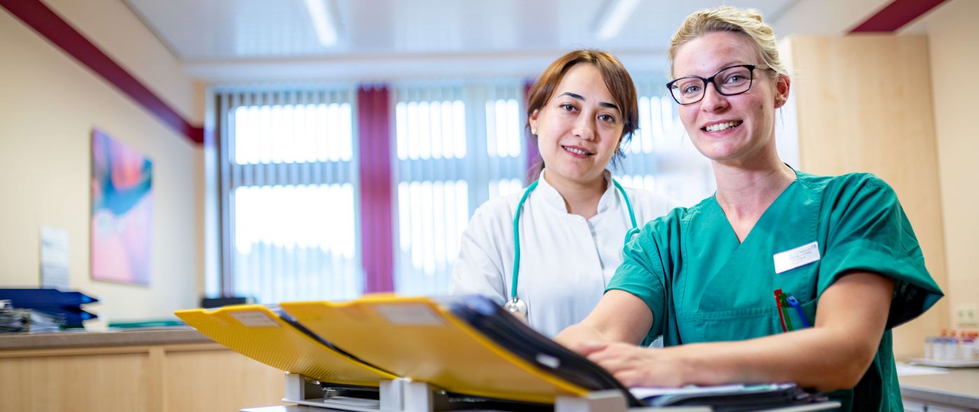 Ärztin und weibliche Pflegekraft besprechen Patientenakten