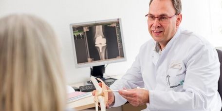 Arzt erklärt die Funktion eines Kniegelenks am Modell