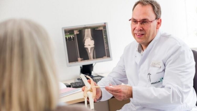 Arzt erklärt die Funktion eines Kniegelenks am Modell