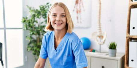  Junge blonde Frau in Physiotherapeutenuniform, die in einer Reha-Klinik steht