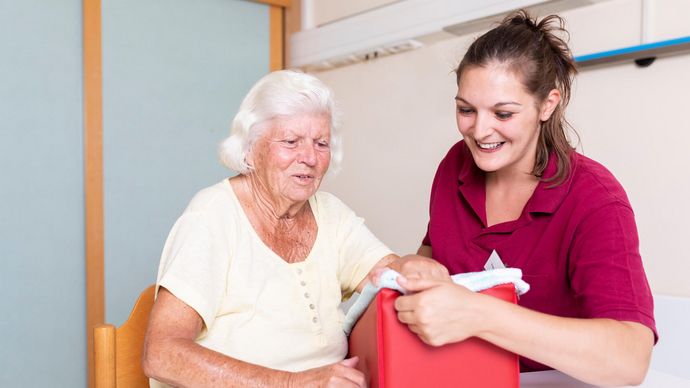 Therapeutin unterstützt ältere Patientin in der Ergotherapie