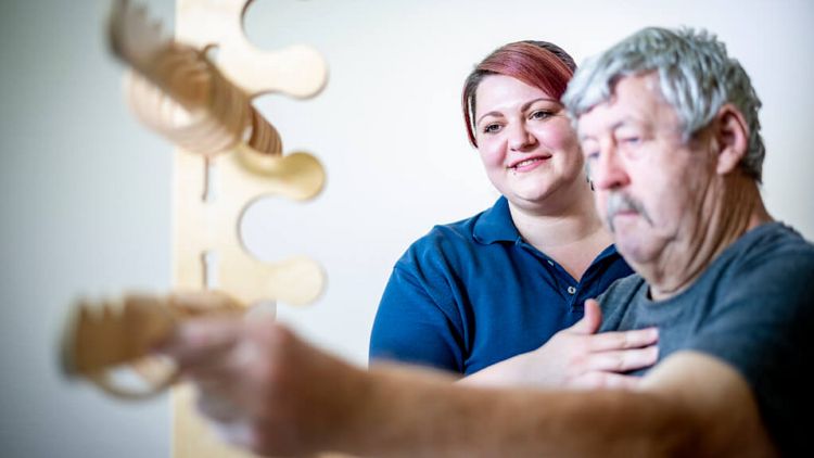 Ergotherapeutin übt mit Patient Feinmotorik