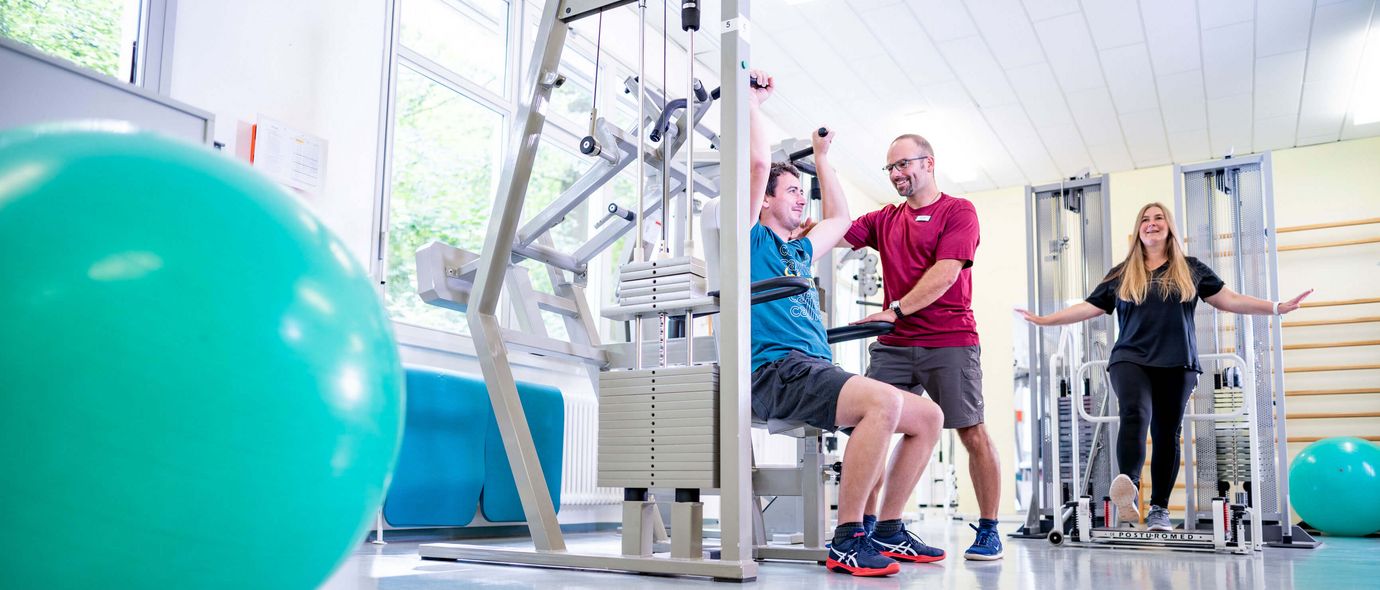 Therapeut unterstützt Pateinten bei der medizinischen Trainingstherapie