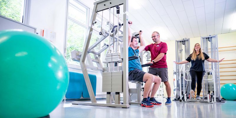 Therapeut unterstützt Pateinten bei der medizinischen Trainingstherapie