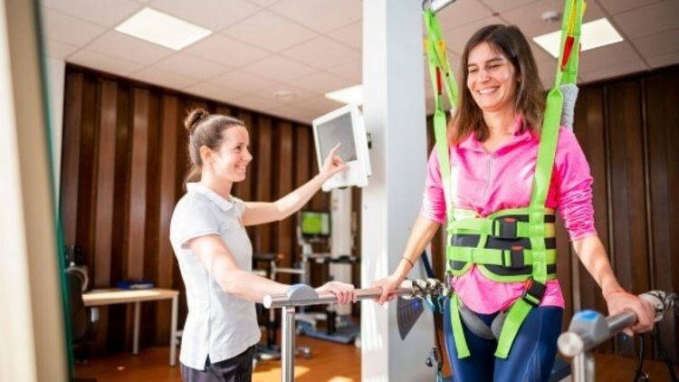Therapeutin trainiert Patientin im Gangtrainer
