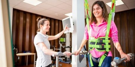 Therapeutin trainiert Patientin im Gangtrainer