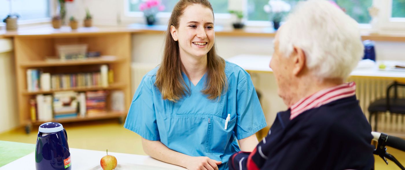 Eine Logopädin hilft einem älteren Patienten beim Essen