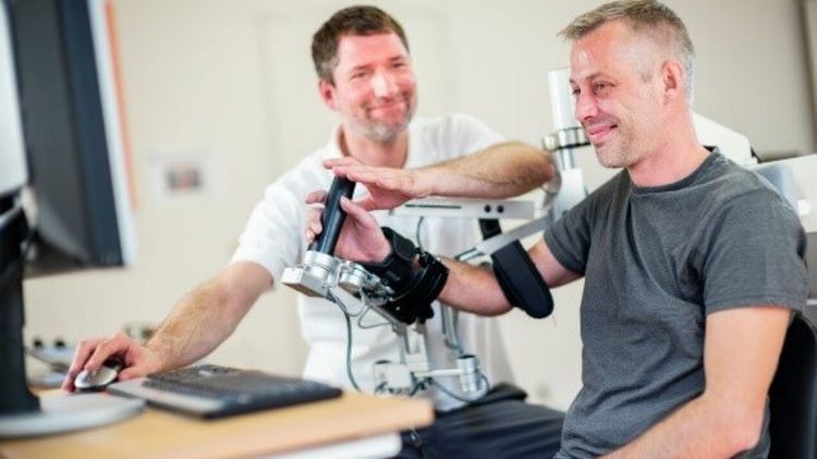 Patient trainiert mit einer Armschiene