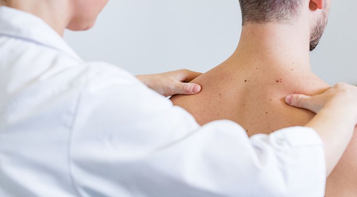 Arzt prüft Rücken des Patienten