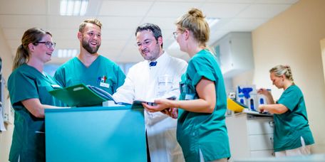 Chefarzt und Pflegekräfte besprechen eine Patientenakte