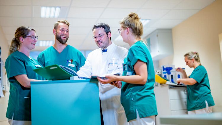 Chefarzt und Pflegekräfte besprechen eine Patientenakte