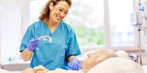 Eine Pflegekraft steht am Patientenbett
