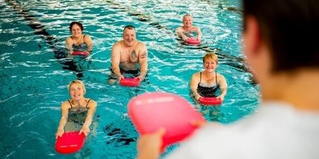 Therapeutin motiviert Patienten bei der Wassergymnastik