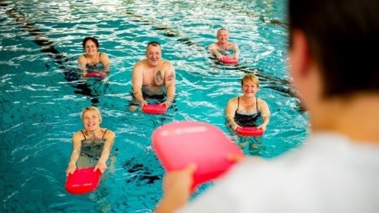 Therapeutin motiviert Patienten bei der Wassergymnastik