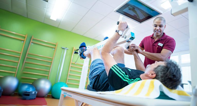 Therapeut unterstützt Patienten beim Training 