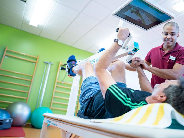 Therapeut unterstützt Patienten beim Training 