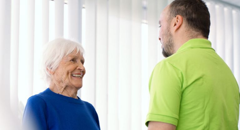 Eine ältere Dame spricht mit einem Physiotherapeuten