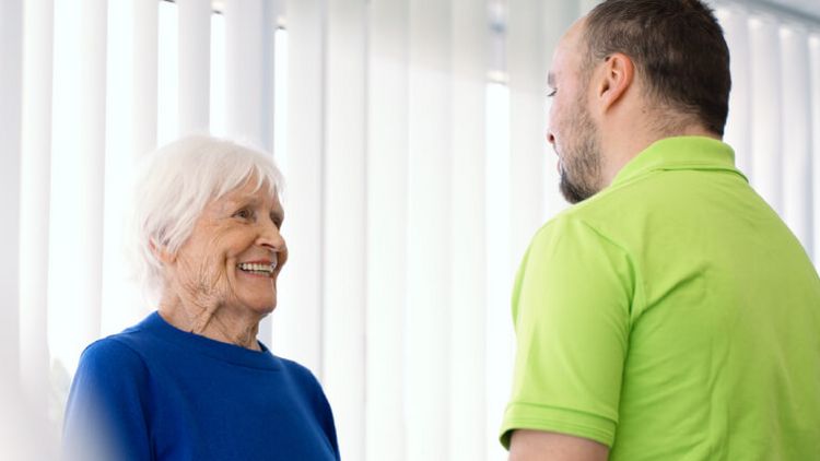 Eine ältere Dame spricht mit einem Physiotherapeuten