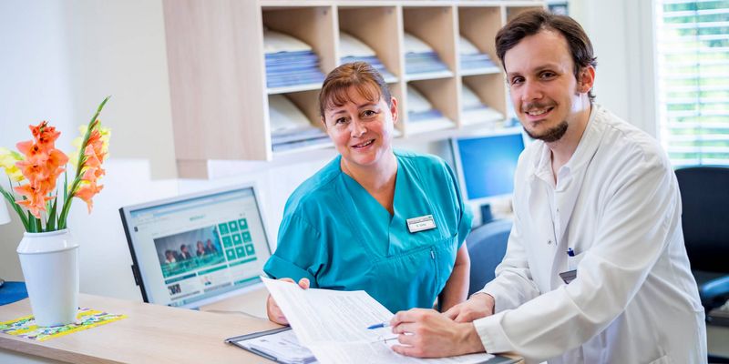 Arzt und Pflegekraft besprechen Patientenakten