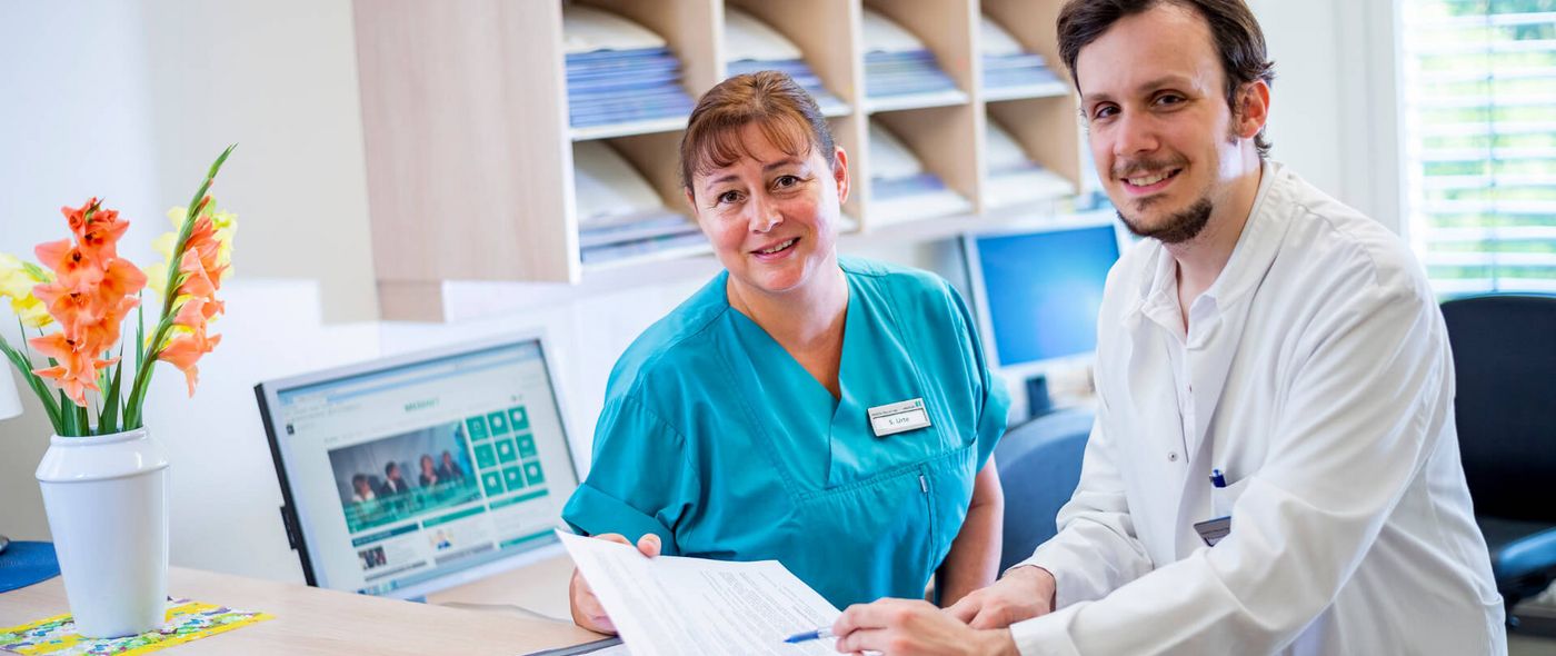 Arzt und Pflegekraft besprechen Patientenakten